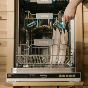 Photo of a person loading a dishwasher with plates