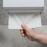 A person pulling a hand towel from a dispenser