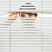 Person looking through a venetian blind