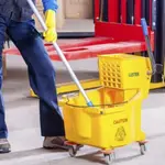 Cleaner using a yellow mop and mop bucket