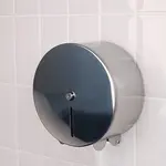 Stainless steel loo roll dispenser fixed to a wall of white tiles