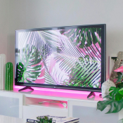 Photo of a television on a white cabinet with pink backlighting.