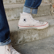 Photo of a persons feet, wearing white converse on concrete steps
